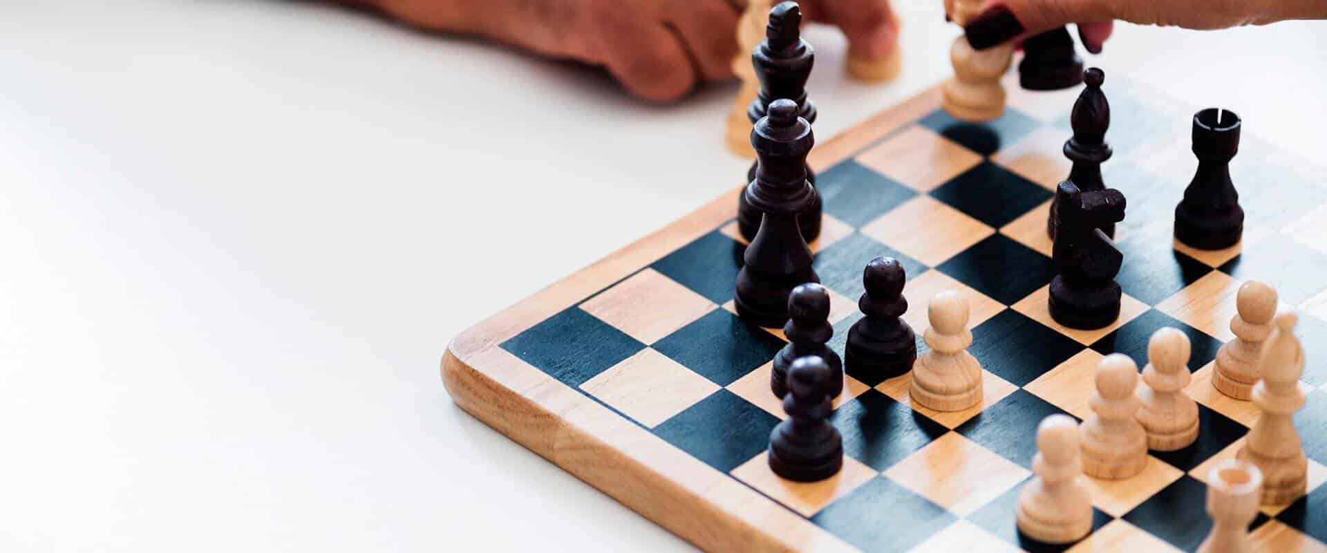 Chessboard with persons hand planning next move - Tisser Law Group